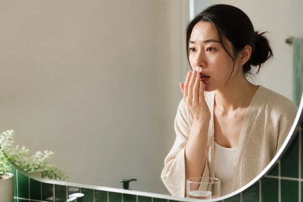 一位成年人在早晨用手輕輕遮住嘴巴，神情有些在意。